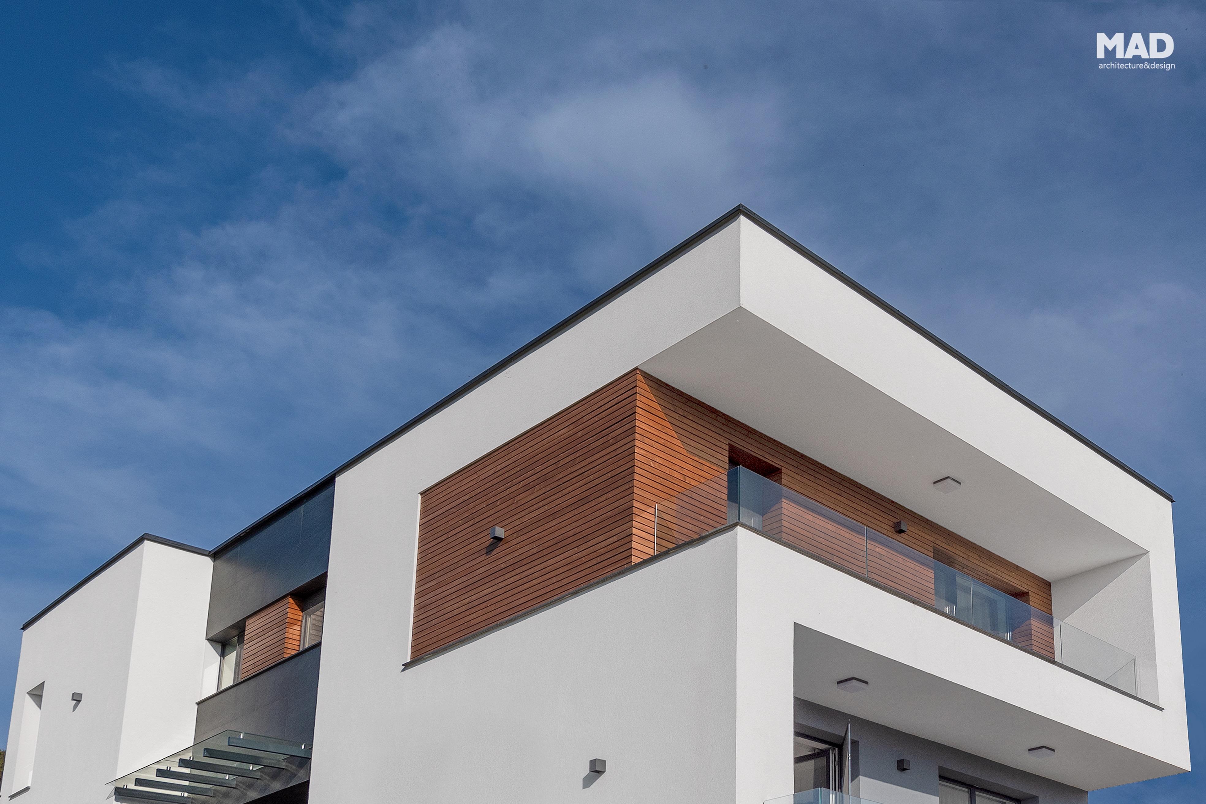 Detaliu al etajului superior al unei case moderne, D+P+E, cu placaj de lemn și tencuială albă, proiect semnat MAD architecture&design.
