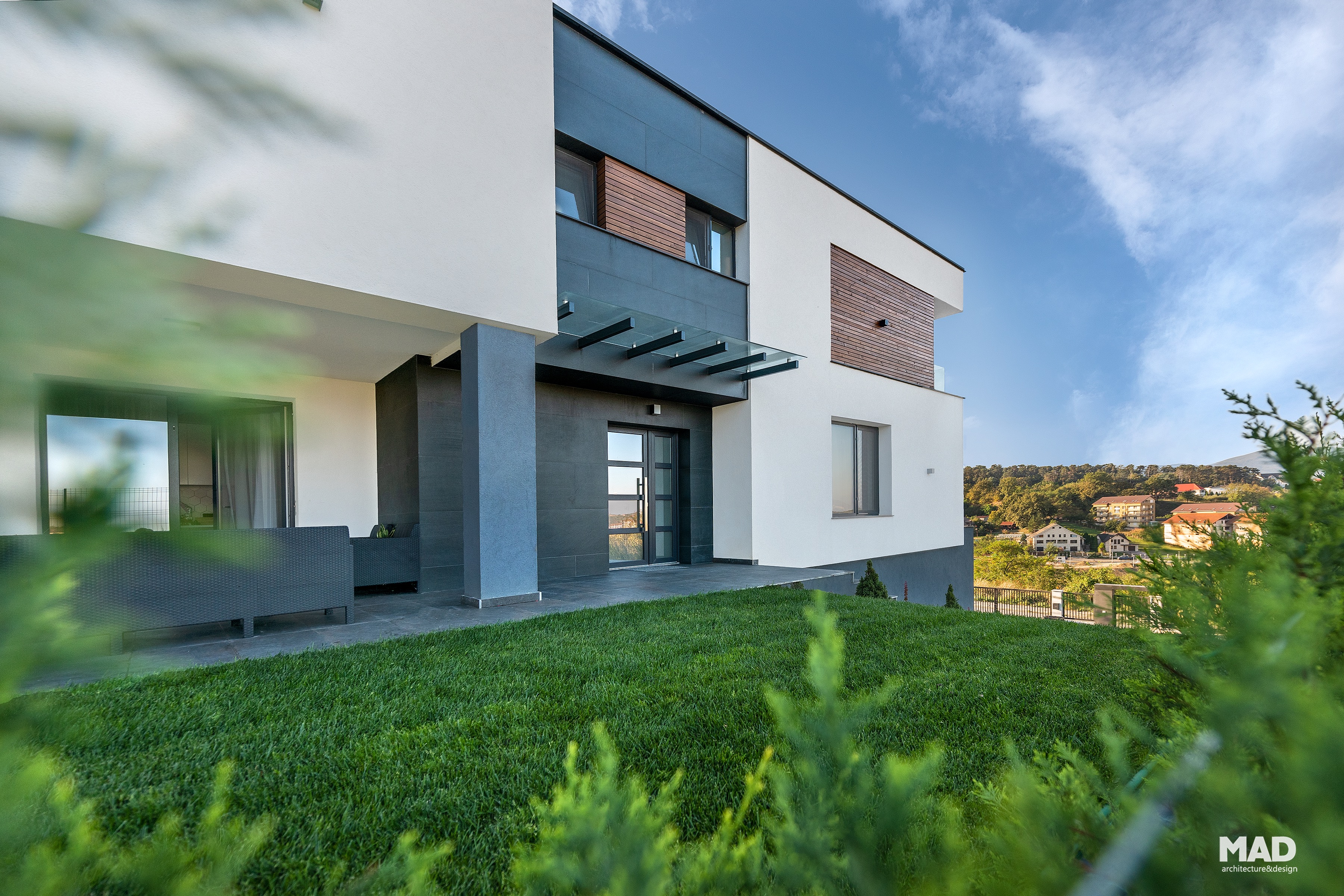 Intrare principală modernă a casei G, proiect MAD architecture&design, cu placare de ardezie, sticlă securizată și tencuială albă.