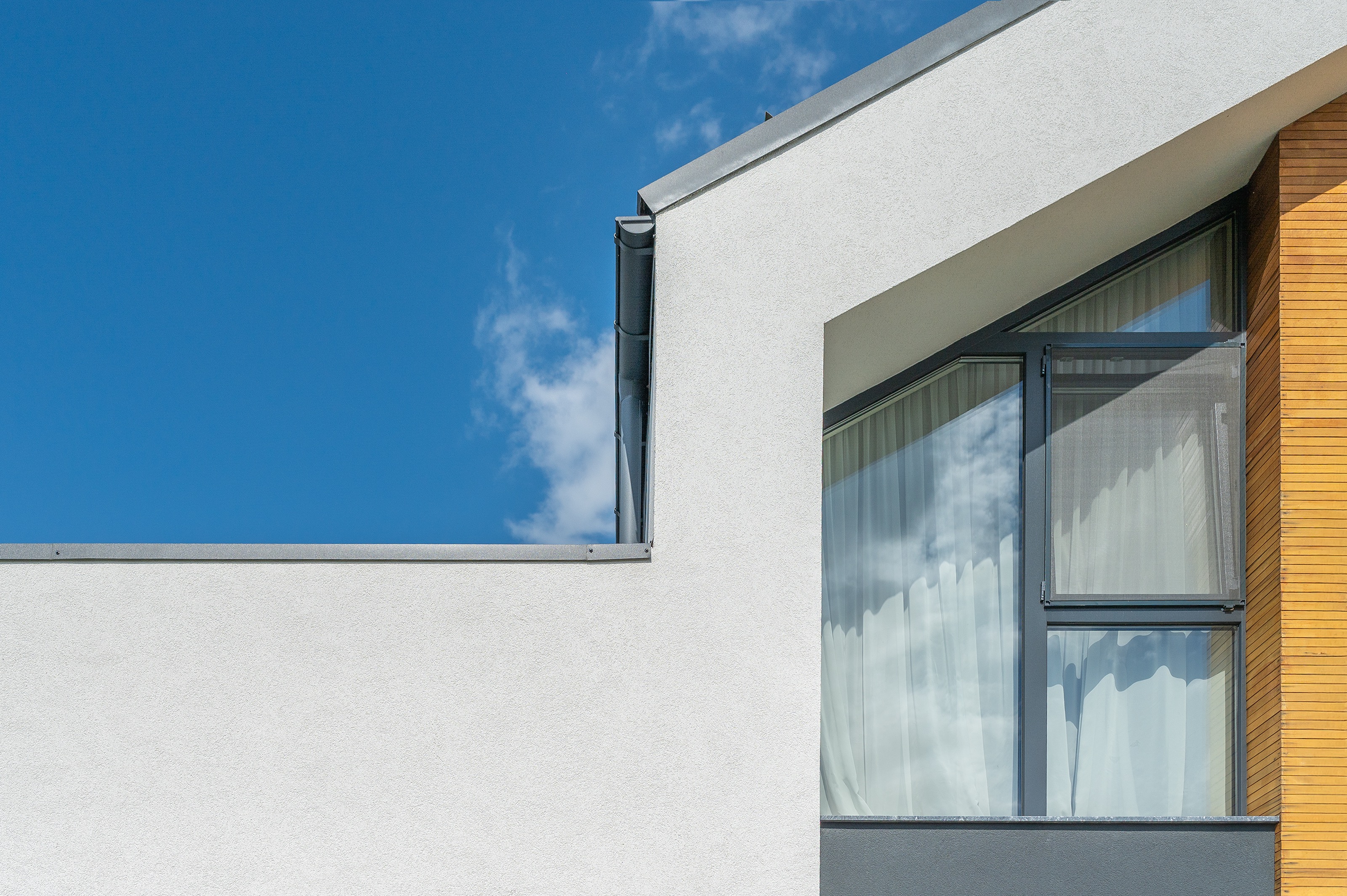 Detaliu arhitectural Casa U, P+1, proiect MAD architecture&design, geamuri mari și fațadă cu placaj de lemn și tencuială albă, stil modern integrat în peisajul din Chinteni