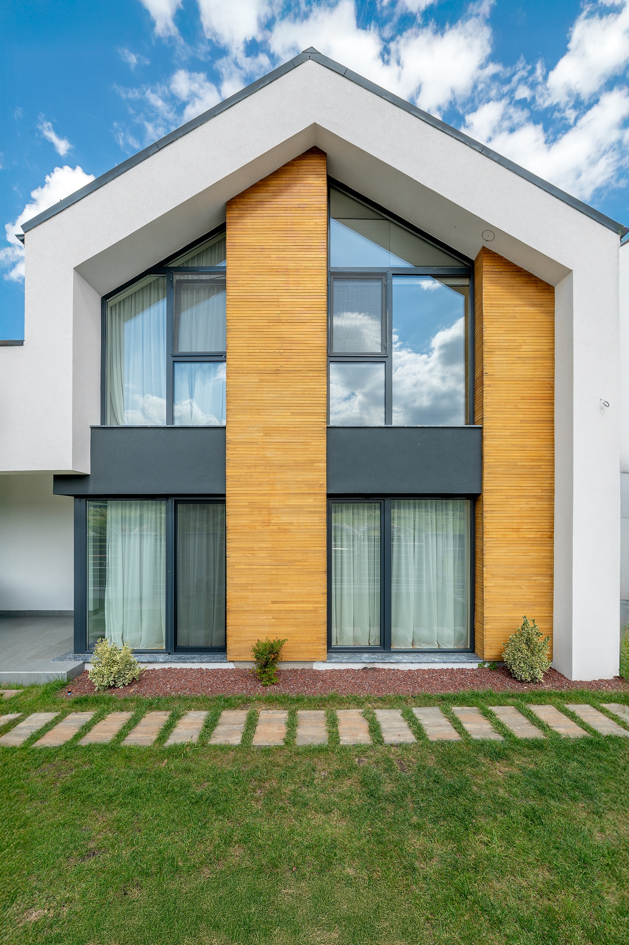 Casă modernă cu regim de înălțime parter și etaj, arhitectură contemporană MAD architecture&design, finisaje din tencuială albă, gri antracit și lemn natural, detaliu al fațadei principale.