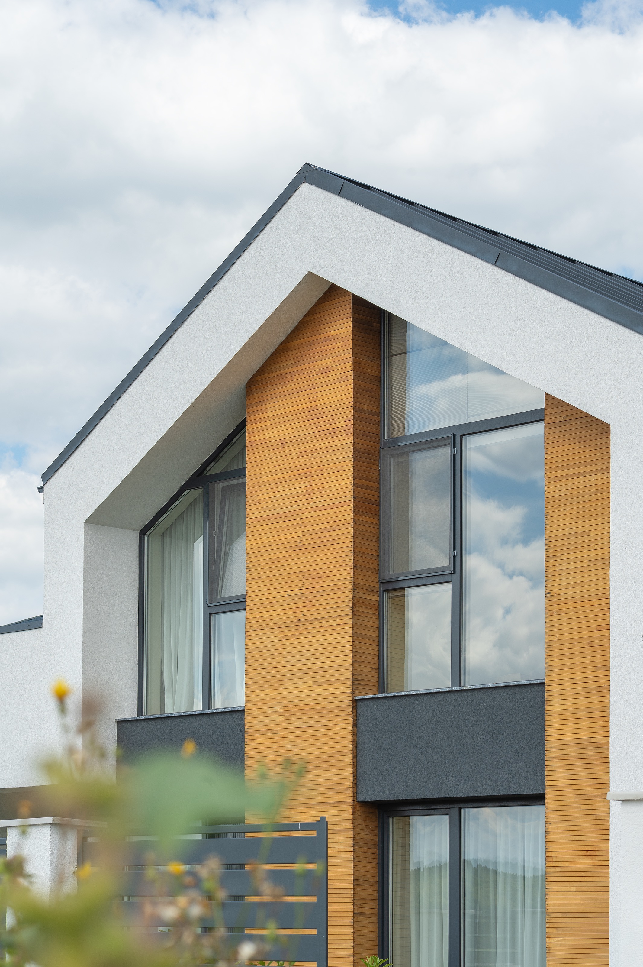 Casă modernă P+1 Casa U, realizată de MAD architecture&design, arhitectură contemporană cu placaj de lemn natural, tencuială albă și ferestre mari, amplasată pe dealurile din Chinteni.