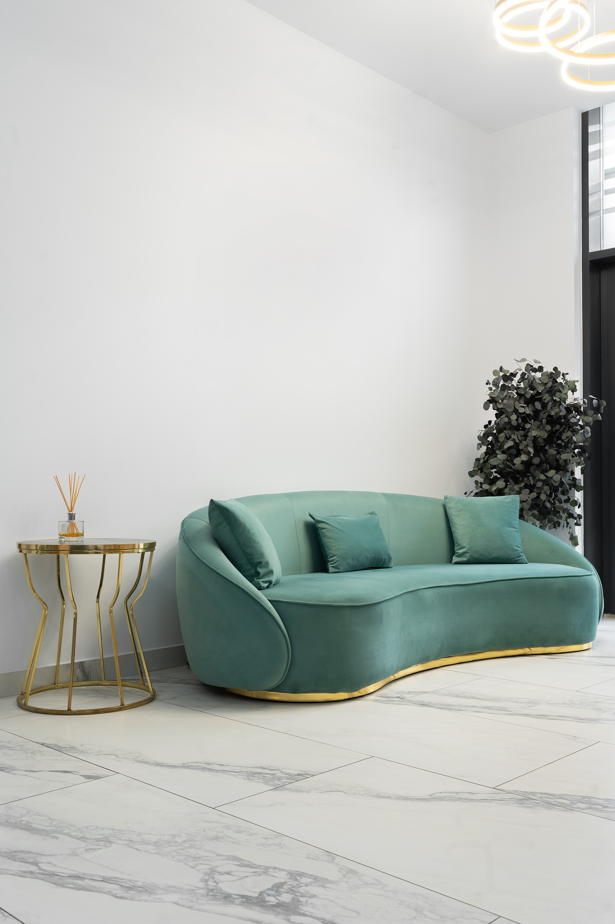Zonă de așteptare în The Nest Dental Clinic amenajată de MAD architecture&design, cu canapea din catifea verde menta turcoaz, măsuță aurie și pardoseală din gresie cu aspect de marmură calacatta.