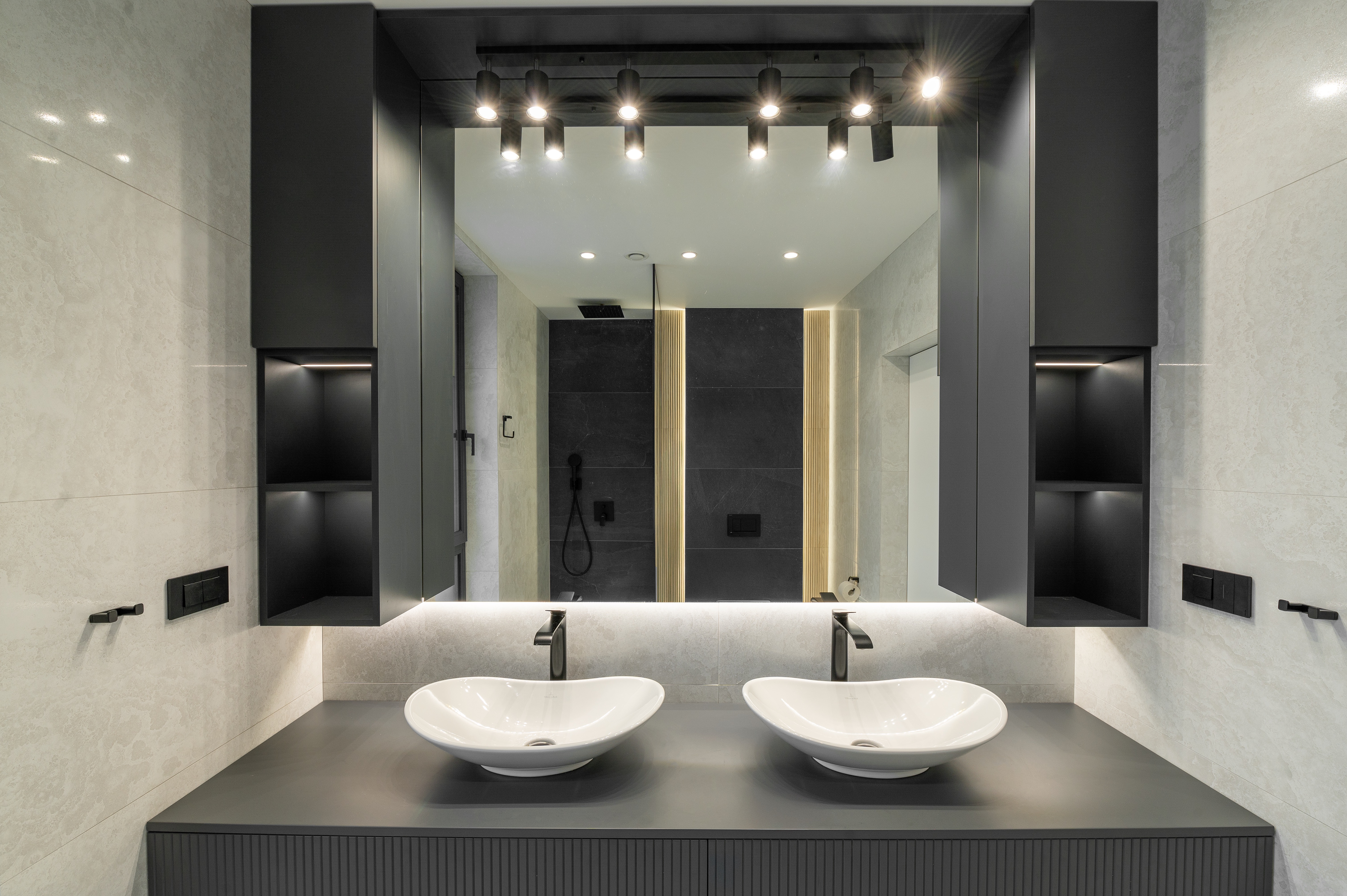 Baie matrimonială în stil contemporan cu mobilier gri mat, blat cu două lavoare tip bol albe, oglinzi luminate LED și accente negre mate – design realizat de MAD architecture&design.