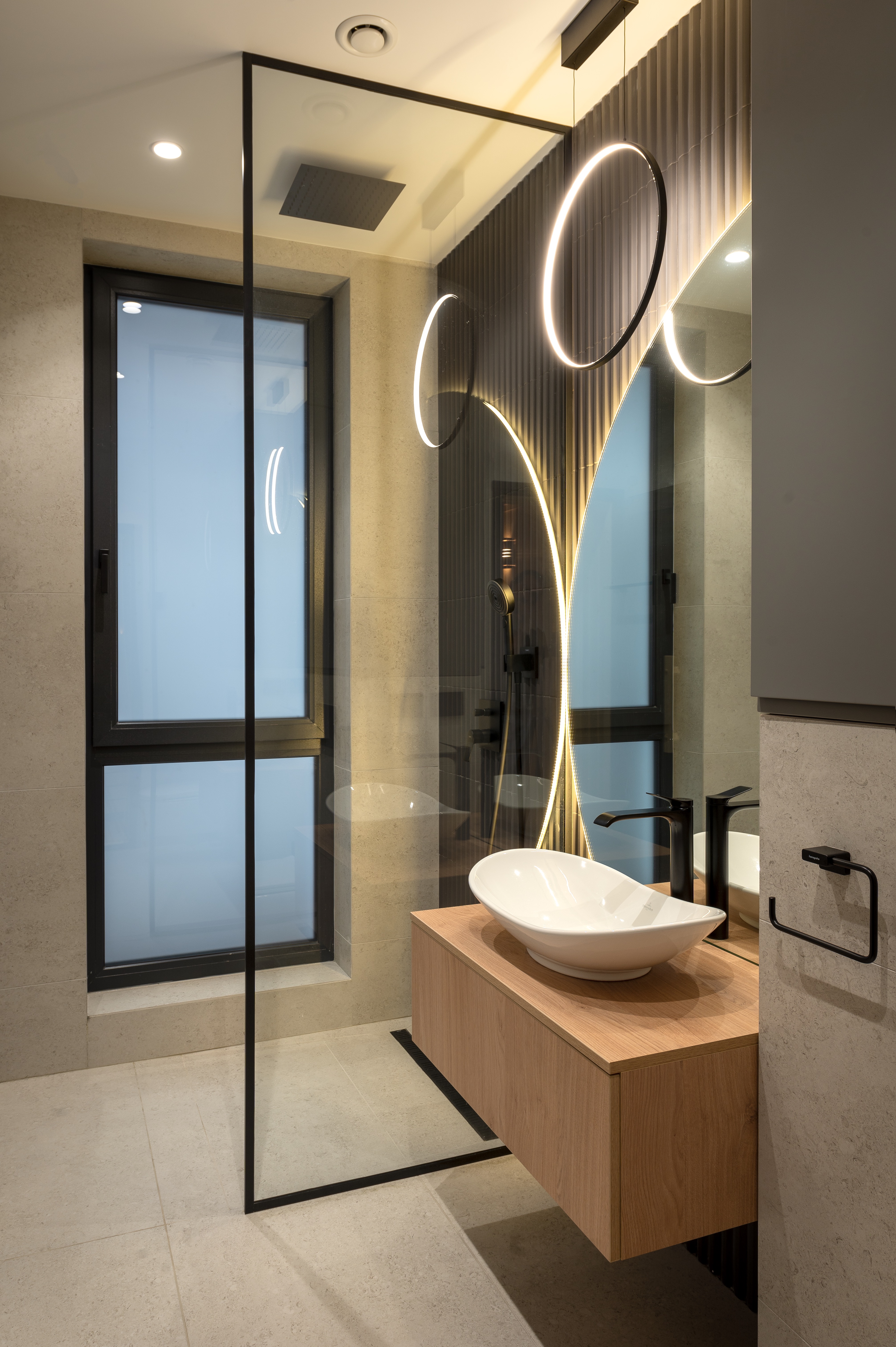 Baie modernă cu paravan de duș din sticlă transparentă, mobilier suspendat din lemn, lavoar tip bol și corpuri de iluminat circulare – MAD architecture&design.