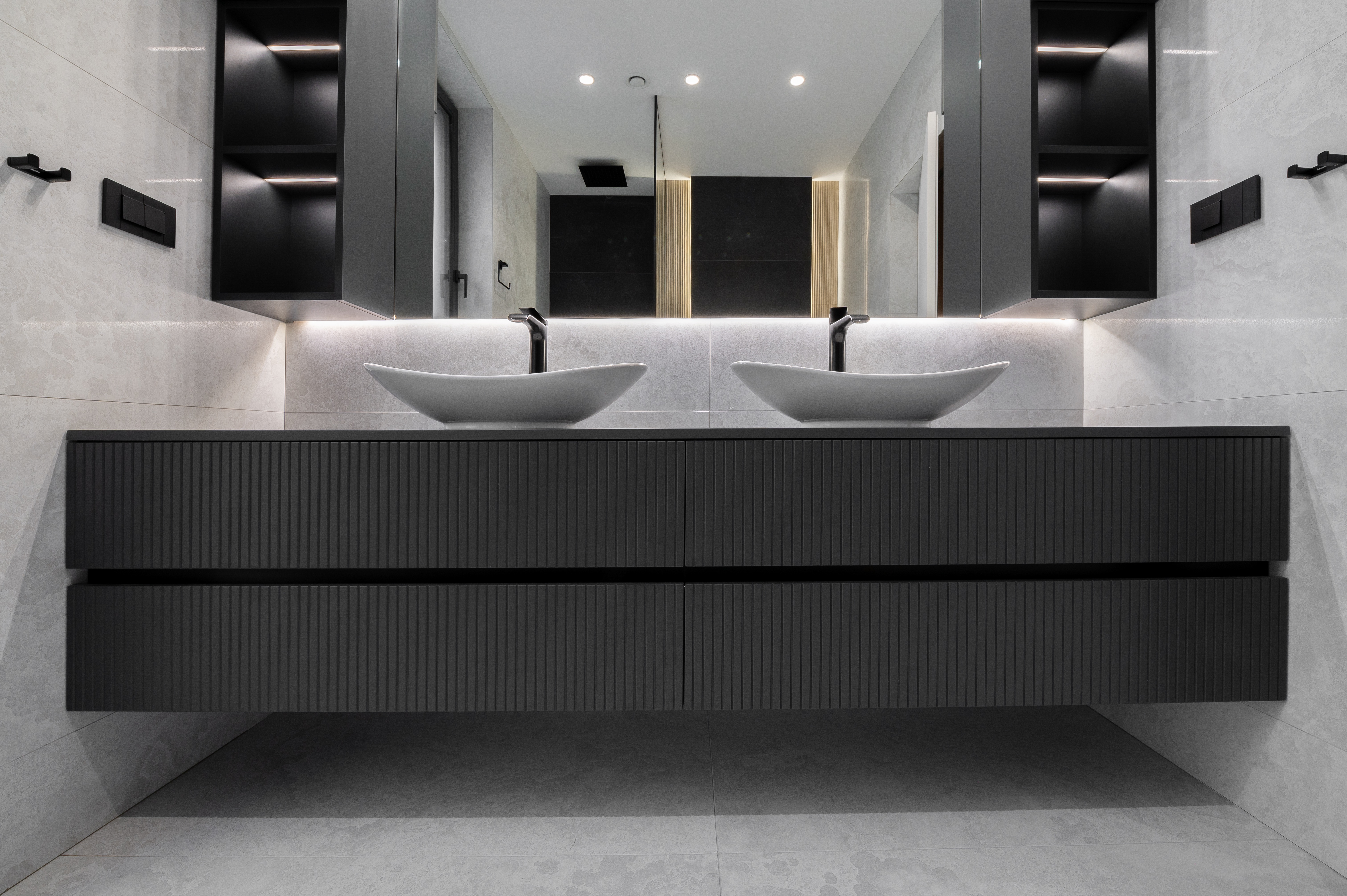 Baie matrimonială elegantă, cu mobilier suspendat gri antracit, fronturi striate, două lavoare albe tip bol și oglinzi cu iluminare LED – MAD architecture&design.