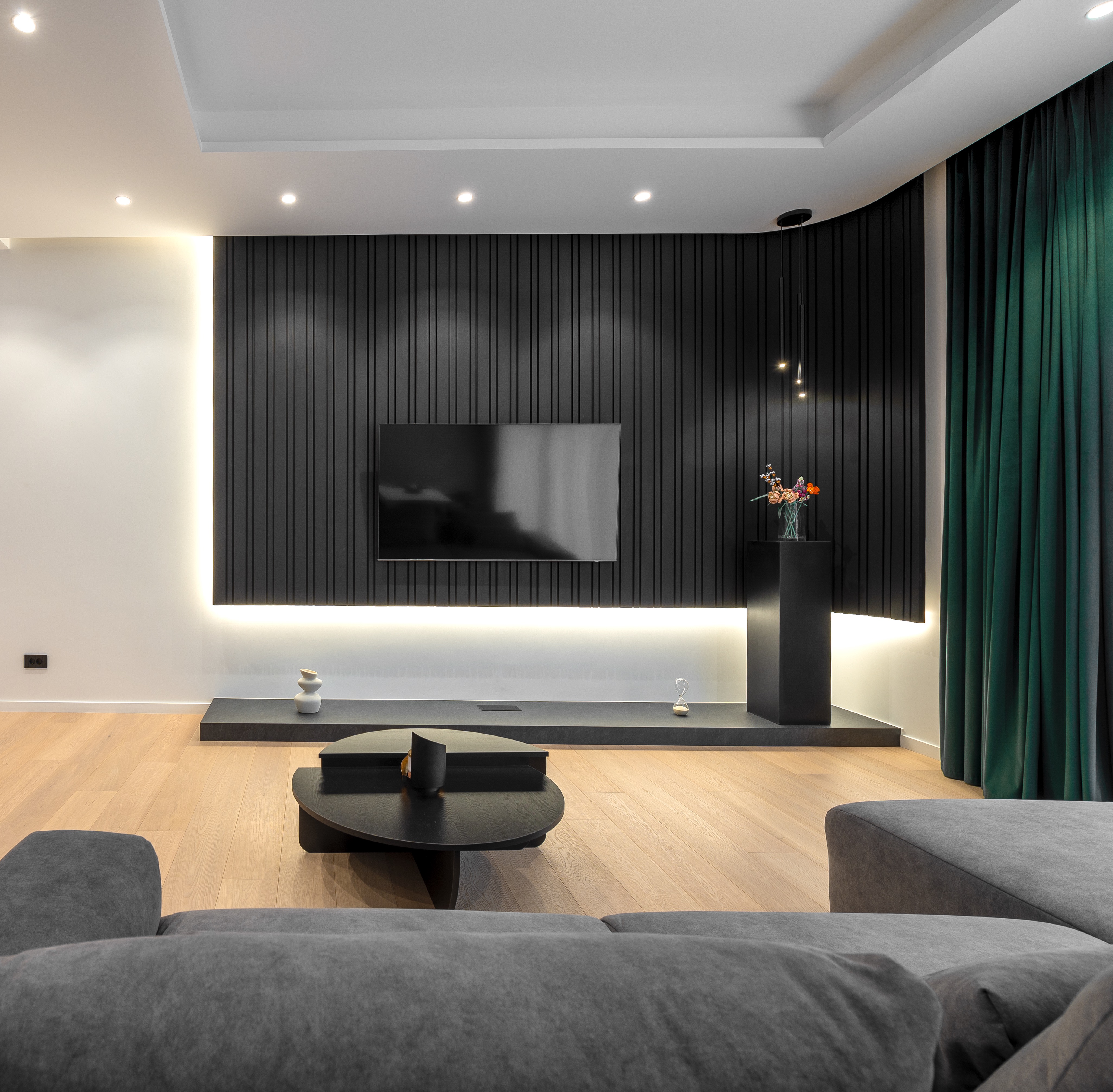 Panou TV elegant din lamele verticale negre, iluminat LED, cu elemente decorative minimaliste și finisaje naturale din lemn – MAD architecture&design.