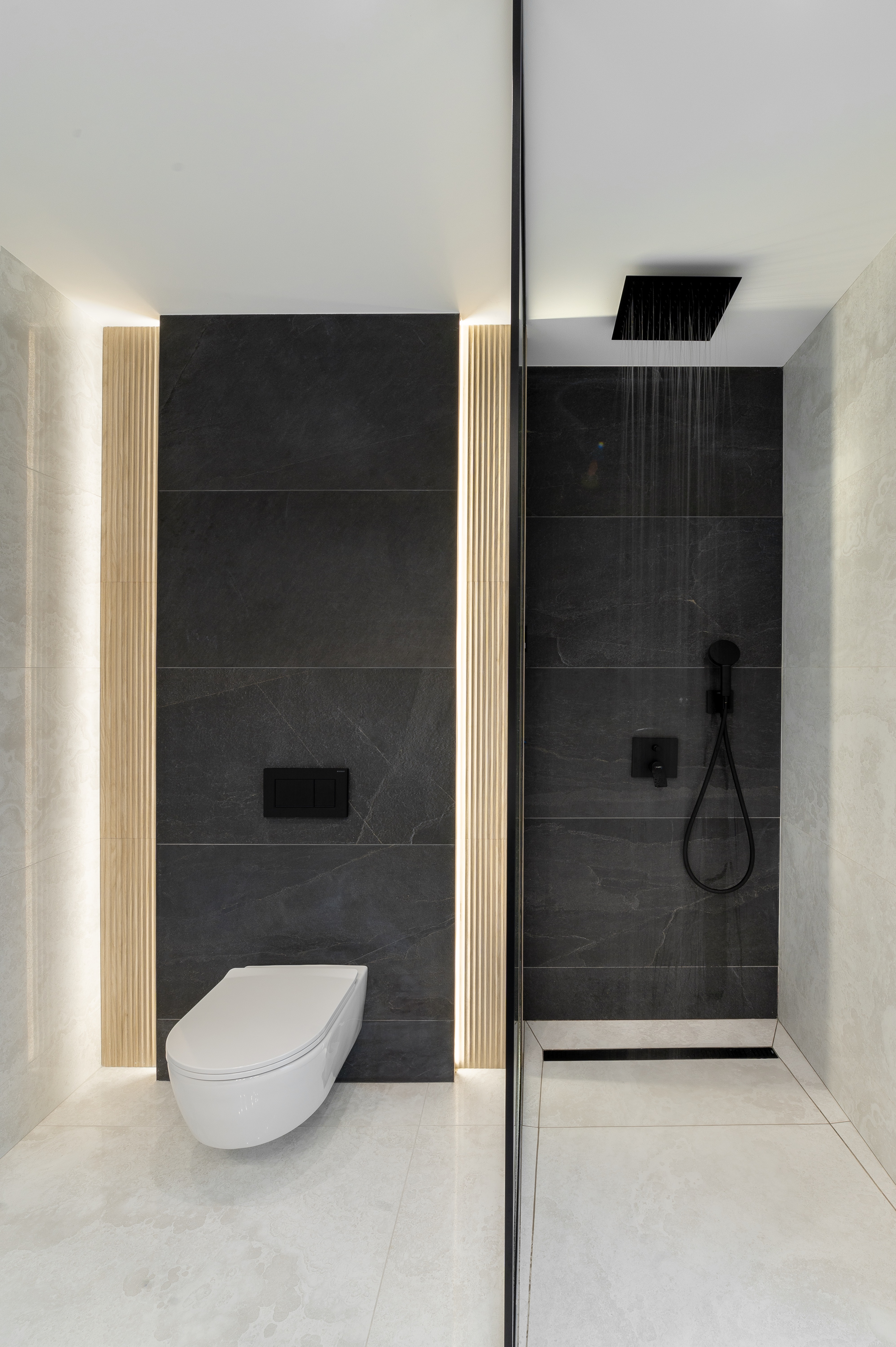 Baie modernă cu duș tip walk-in, placaje ceramice gri închis și deschis, paravan de sticlă și elemente negre mate, în stil minimalist – MAD architecture&design.